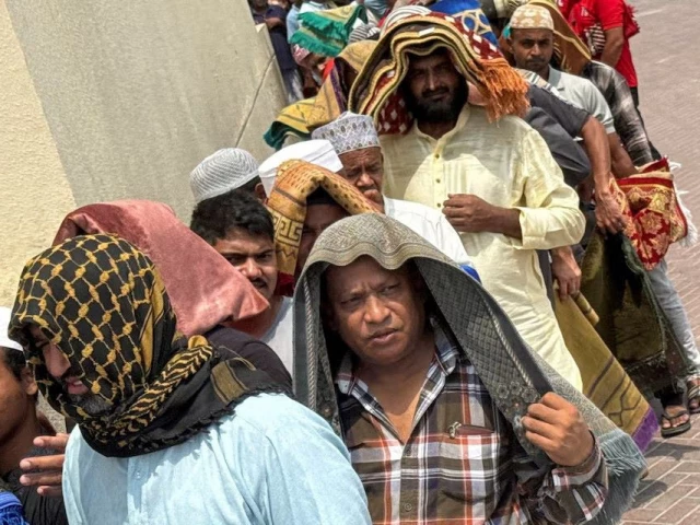 people cover their heads with prayer rugs for shade following friday prayers during the summer heat in dubai united arab emirates august 1 2025 photo reuters