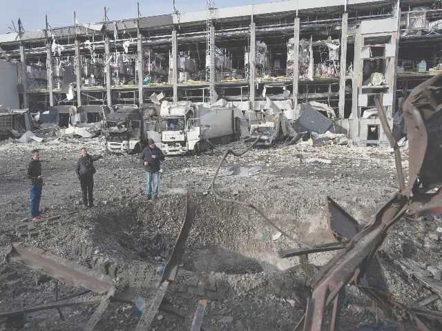 law enforcement officers inspect a crater next to the heavily damaged logistics hub of the novus supermarket following russian missiles and drones strikes in kyiv photo afp