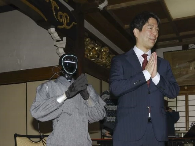 seiji kumagai professor at kyoto university stands next to a humanoid monk robot in kyoto western japan on feb 24 2026 photo kyodo news