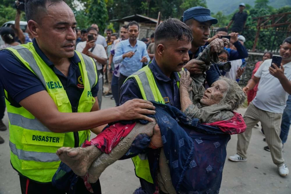 Rescuers carry a victim of flash flooding to safety along the Trishuli River in Nepal